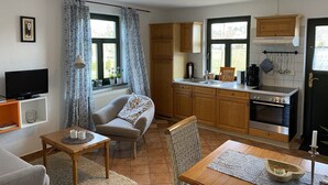 A compact living space with a kitchenette, a sofa, a TV, and a dining area. - Wohnung in Dargun, Mecklenburg mit Schwimmbad (Dargun)