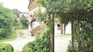 A courtyard with a wooden staircase leading to a white building with a brown facade.