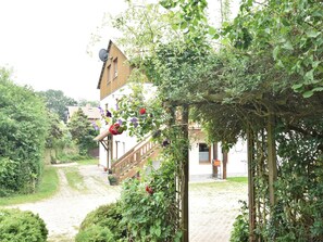 Traditional European-style building with a wooden staircase and lush greenery surroundings.