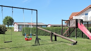 A playground with swings, a slide, and a climbing structure. - Wohnung mit Terrasse in Klutz (Klütz)