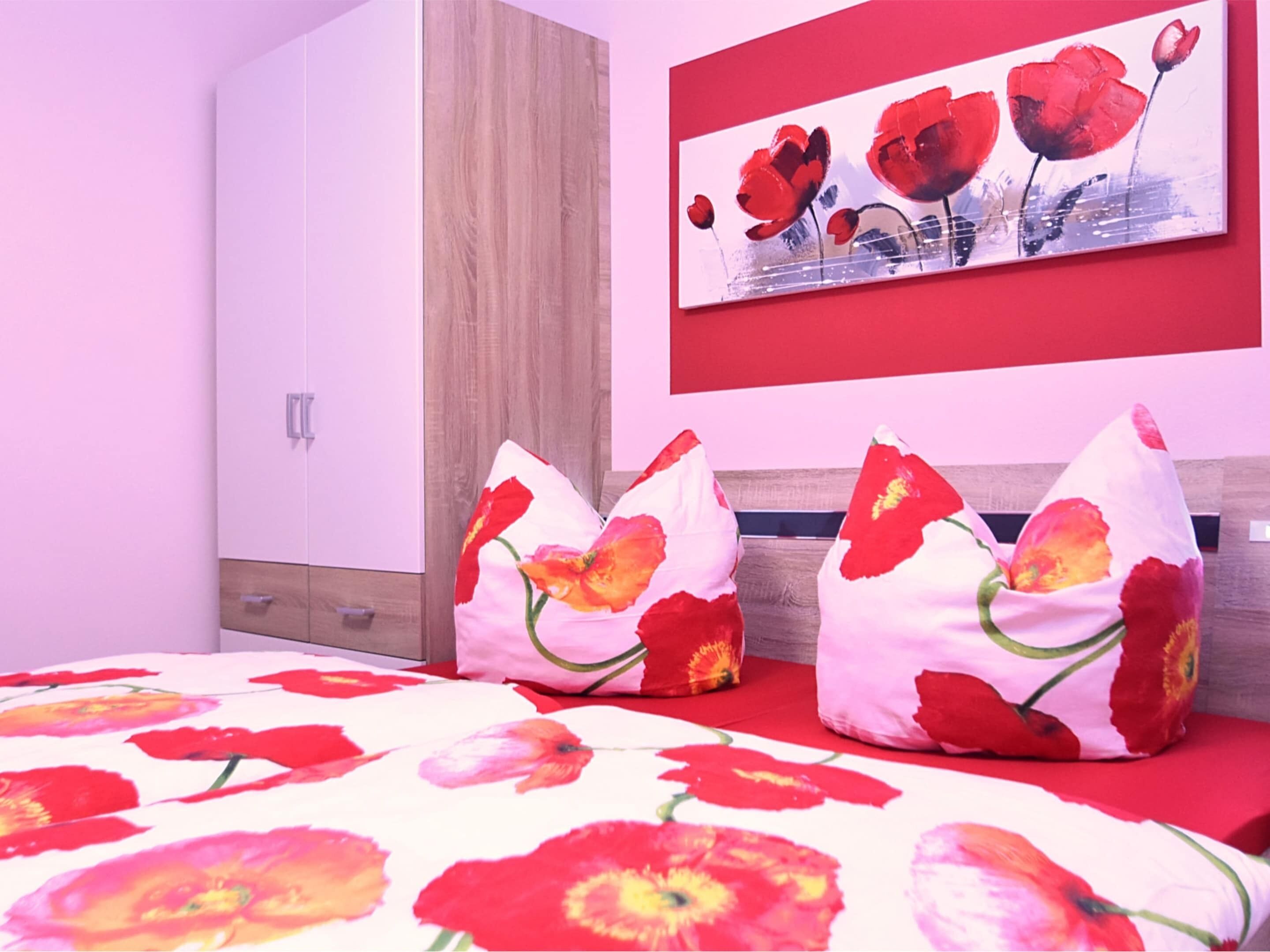 A bedroom with a bed, pillows, a painting, and a wardrobe.