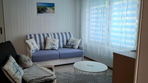 A living room with a striped sofa, a small round table, and a black chair. - Romantic Retreat in Kropelin (Kroepelin)