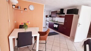 A compact kitchen with a dining area, a clock, and a washing machine. - Romantic Retreat in Kropelin (Kroepelin)