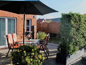 A patio with a glass table, chairs, and a black umbrella.
