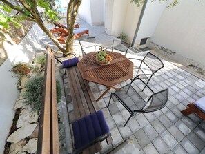 En terrasse med et træbord, metalstole og en bænk.