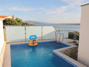 A swimming pool with a blue tiled edge, a small inflatable float, and a metal ladder. - Modern Apartment With Private Pool in Maslenica (Jasenice)