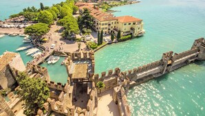 A coastal town with a historic fortification, a marina with boats, and a prominent building with a red roof. - Holiday Home in Sirmione Near Thermal Baths (Sirmione)