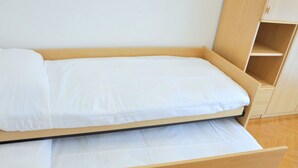 A single bed with a wooden frame and white bedding in a room with a herringbone-patterned floor and a white wall. - Holiday Home in Sirmione Near Thermal Baths (Sirmione)