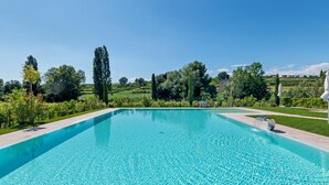 Ein rechteckiger Swimmingpool mit klarem, blauem Wasser, umgeben von einem gepflegten Garten mit verschiedenen Pflanzen und Bäumen.