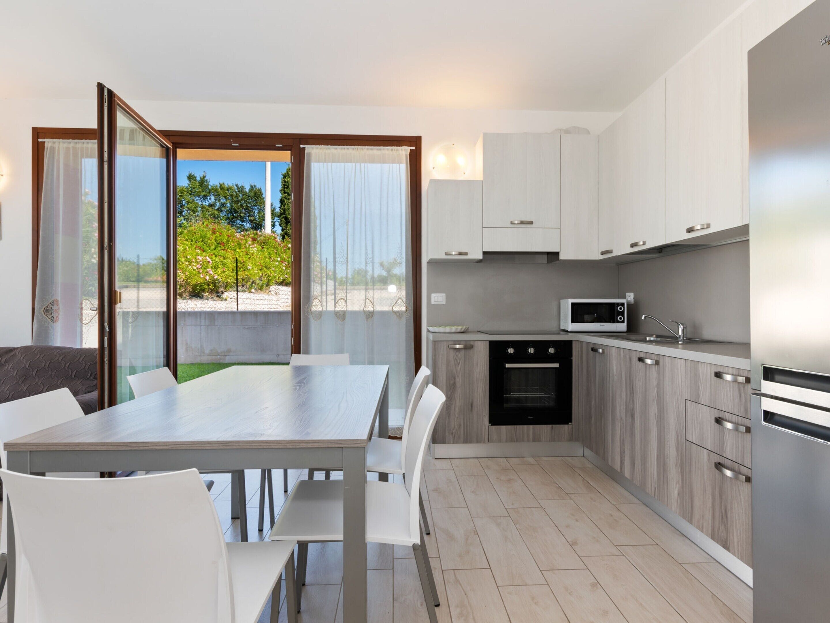 A modern kitchen with white cabinets, a built-in oven, and a microwave.