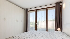 Ein Schlafzimmer mit Bett, Kleiderschrank und einer Glastür zu einem Balkon.
