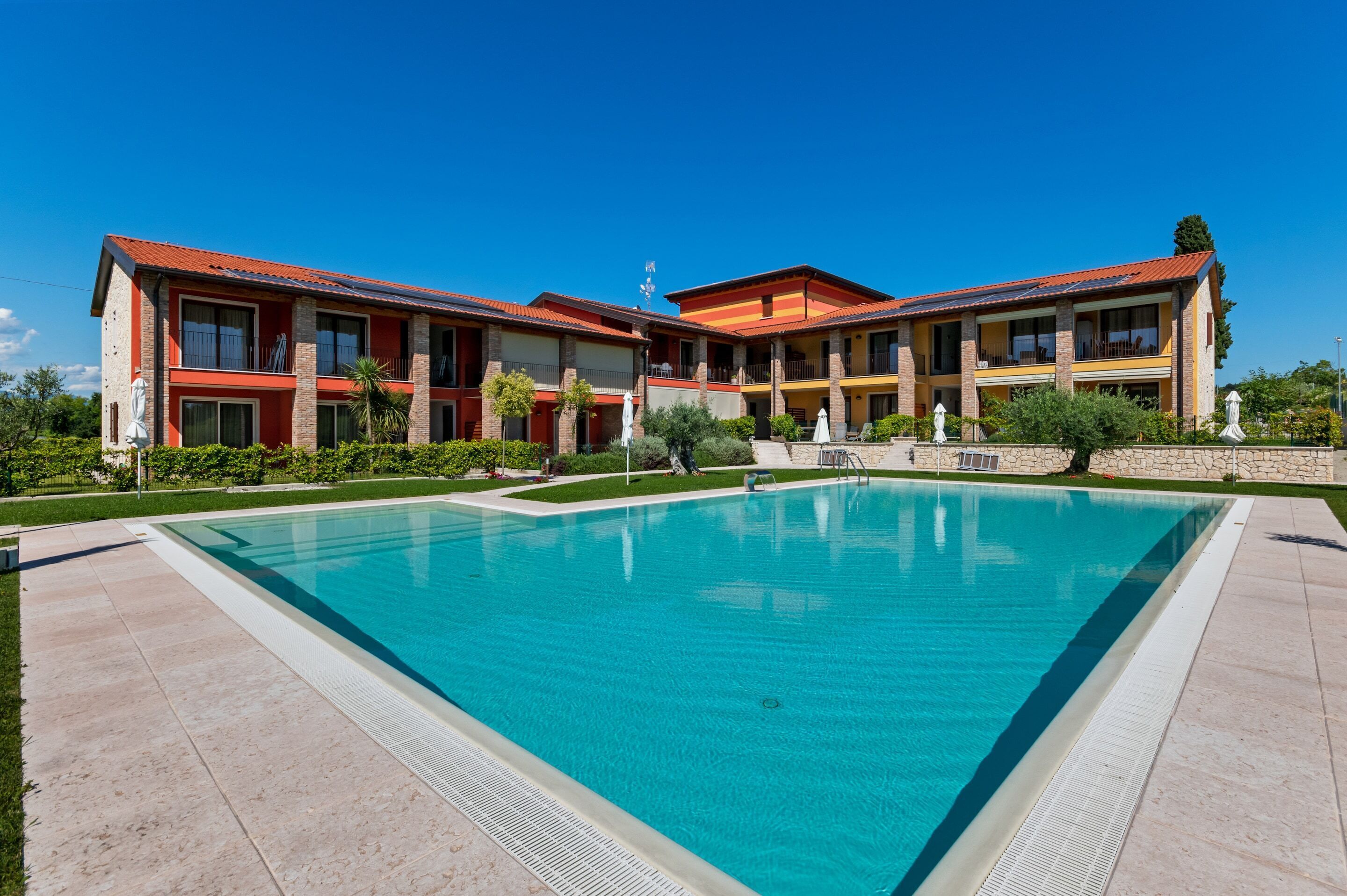 A hotel with a swimming pool, multiple balconies, and a stone facade.