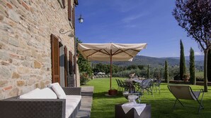 An outdoor patio with a stone wall, wicker furniture, and a table set for dining.