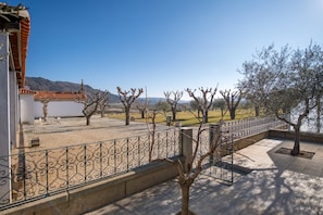 Une cour avec un sol carrelé, une clôture en métal et des arbres.
