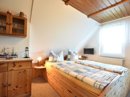 Um quarto aconchegante com uma cama beliche de madeira, uma mesa de cabeceira com abajur, uma cômoda e uma janela com cortinas.