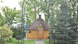 A wooden cabin with a tiled pathway leading to it, surrounded by greenery and trees. - Wohnung in Wiek Nahe Juliusruh Strand (Wiek)