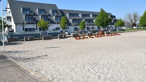 A hotel with a modern design, featuring multiple balconies and a sandy beach area with sun loungers. - Wohnung in Wiek Nahe Juliusruh Strand (Wiek)