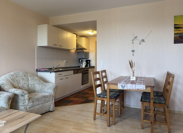 A compact living space with a kitchenette, a dining area with a table and chairs, and a sofa.