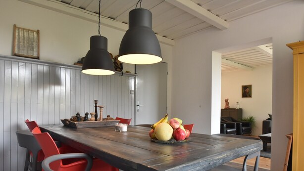 A dining area with a wooden table, red chairs, and a fruit bowl. There are two pendant lights above the table. - Chalet in Levinska Ole Near Giant Mountains (Levínská Olešnice)