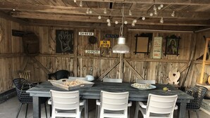 A rustic dining area with a wooden table, white chairs, and a hanging light fixture. - Chalet in Levinska Ole Near Giant Mountains (Levínská Olešnice)