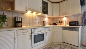 A kitchen with white cabinets, a coffee maker, a toaster, and a dishwasher. - Moderne Ferienwohnung mit Grill in Rakow (Am Salzhaff)