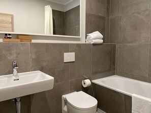 A modern bathroom with a white sink, a toilet, and a bathtub. - Grosszuegige Ferienwohnung mit Garten (Saal)