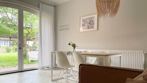 A modern bedroom with a large window, a dining area with chairs, a table, and a hanging light fixture. - Grosszuegige Ferienwohnung mit Garten (Saal)