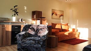 Ein modernes Wohnzimmer mit einer Couch, einem Couchtisch, einem Fernseher und einem Bücherregal.