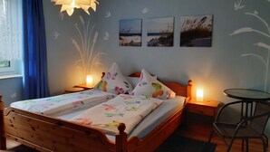 Ein Schlafzimmer mit einem hölzernen Bett, zwei Nachttischen mit Lampen, einem kleinen runden Tisch und einem Stuhl.