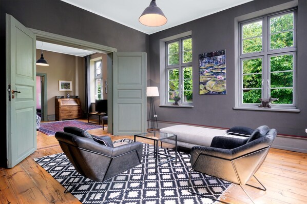 A room with a large window, a sofa, a patterned rug, and a painting on the wall.