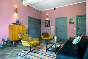 Un salon comprenant un canapé, deux fauteuils, une table basse, un tapis à rayures et un meuble.