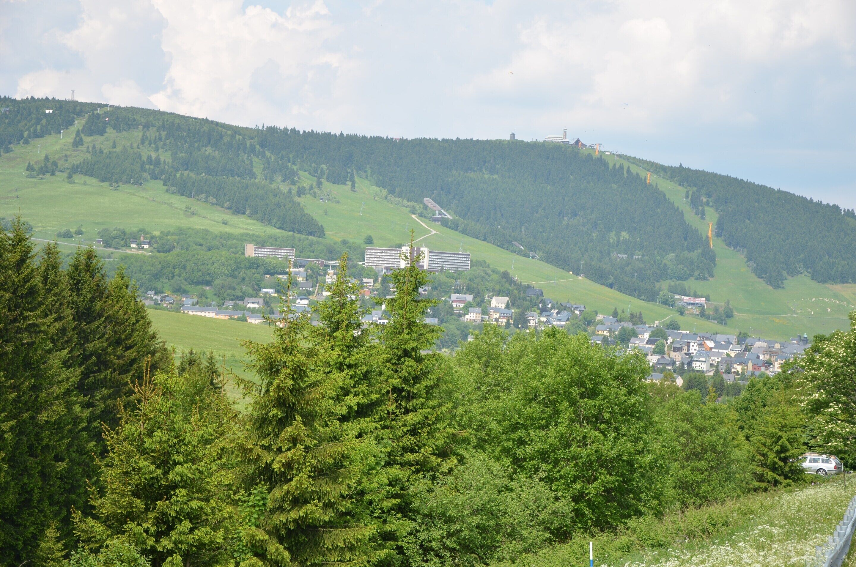 Eine Stadt liegt eingebettet in einem Tal, im Hintergrund ein markantes Gebäudekomplex.
