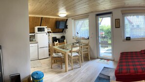 Un espacio habitable compacto con kitchenette, zona de comedor y un sofá rojo acogedor.