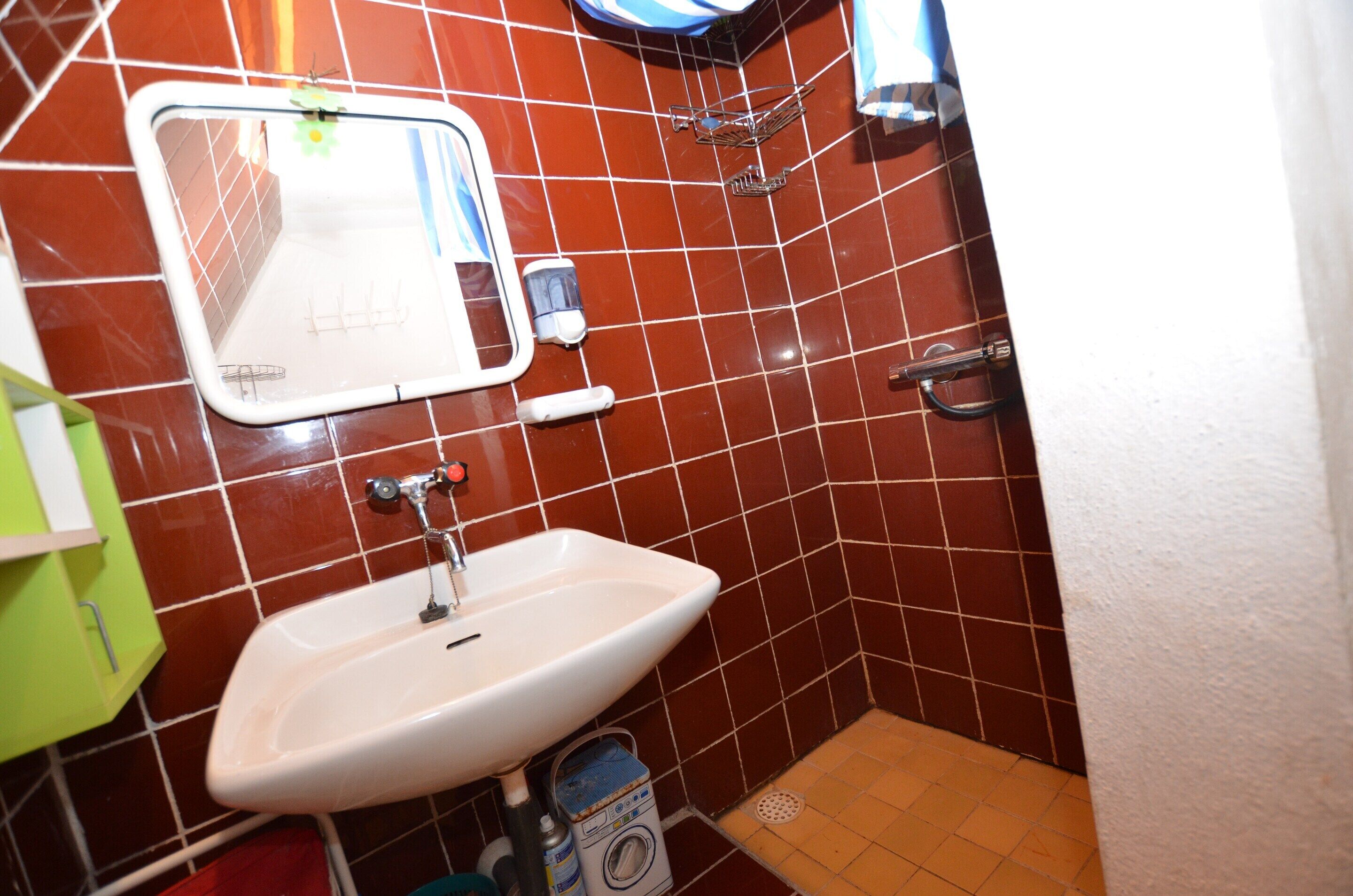 A bathroom with a white sink, a mirror, and a shower area.