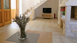 Amplia sala de estar con escalera, un televisor sobre un soporte de madera y una planta en maceta.