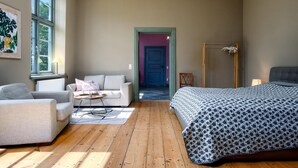 A room with a bed, a sofa, a chair, a table, and a window. - Steffenshagen Vicarage Retreat (Steffenshagen)