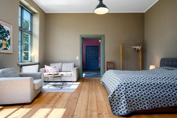 Una habitación con cama, sofá, silla, mesa y ventana.