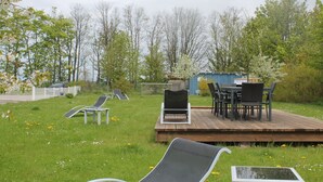 Um deck com móveis de exterior, uma pequena área de jardim e uma estrutura de recreação infantil.