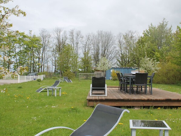 A deck with outdoor furniture, a small garden area, and a playground structure.