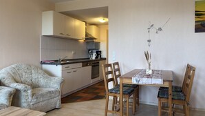 Um espaço compacto com cozinha compacta, área de refeições com mesa e cadeiras, e um sofá.