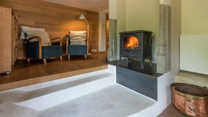 Un accogliente soggiorno con un camino in pietra, una panca di legno e una poltrona blu.