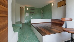 Un bagno moderno con pareti rivestite di piastrelle verdi, una panca in legno e una vasca da bagno.