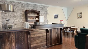 A kitchen with a stone wall, wooden cabinets, a microwave, and a bar area. - Sunny Apartment in Wiek, Rugen (Wiek)