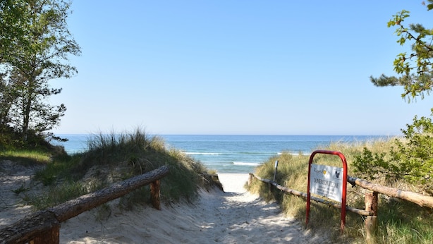 A sandy beach path leading to the ocean with a sign indicating a protected dune area. - Sunny Apartment in Wiek, Rugen (Wiek)