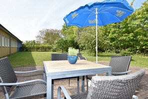 An outdoor patio with a table and chairs, a blue umbrella, and a potted plant. - Sunny Apartment in Wiek, Rugen (Wiek)