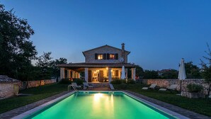Una casa in pietra con piscina, area salotto all'aperto e portico coperto.