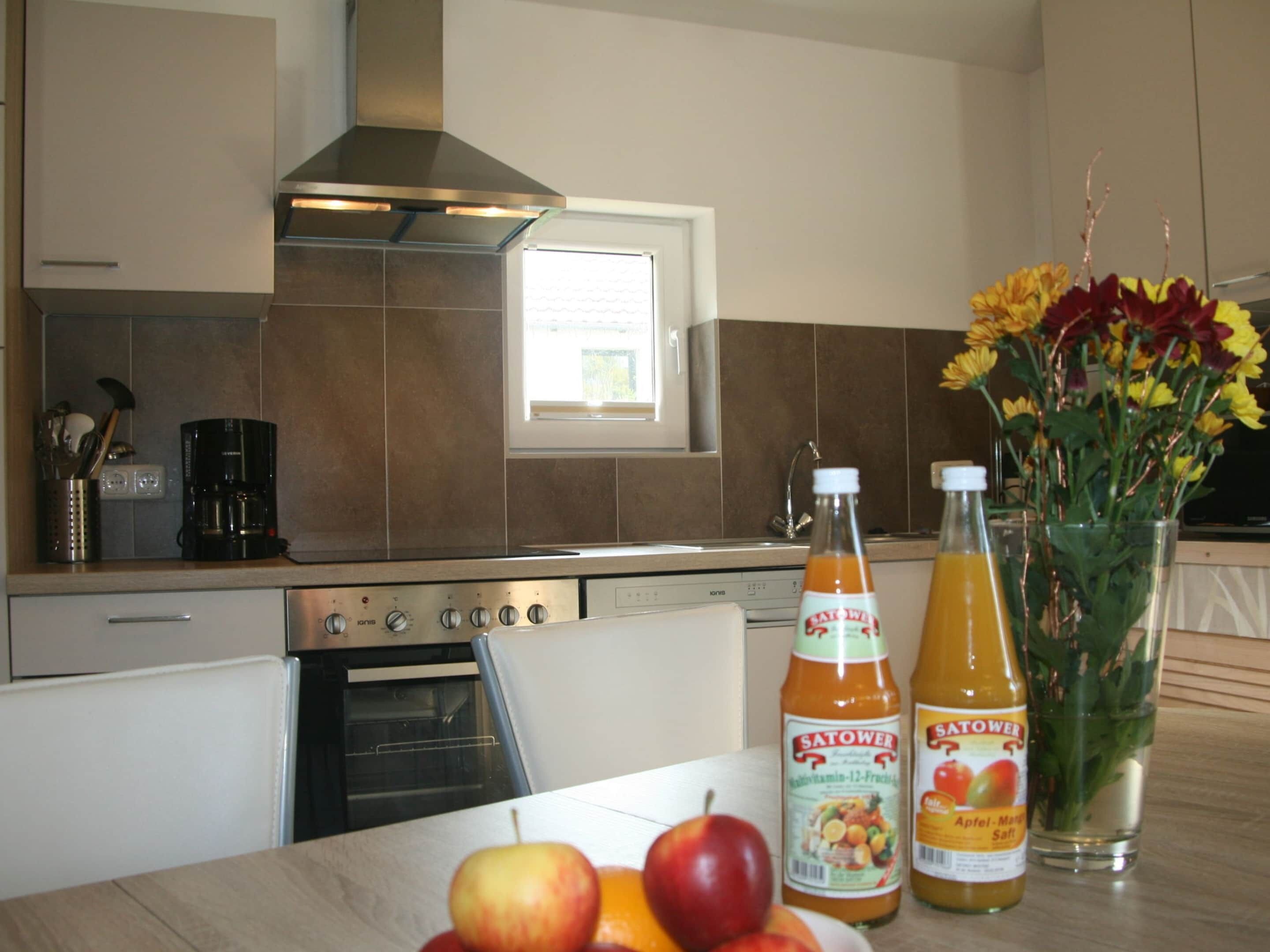 A kitchen with a stove, oven, and a window. There are two bottles of Satower on the counter.