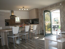 A modern kitchen with a central island, white chairs, and a dining table.