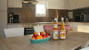 A kitchen with a wooden table, a bowl of fruit, and two bottles of juice. - Elegant Mansion in Bastorf near Sea (Bastorf)