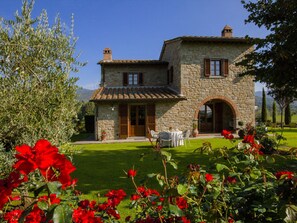 Une maison en pierre avec un toit de tuiles, une porte en bois et une entrée en arc de cercle.